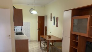 A compact kitchen with a dining area, a TV stand, and a dining table with chairs. - Renovated apartment on the ground floor (Rosolina Mare)