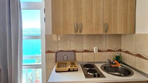 Een compacte keuken met houten kastjes, een wit aanrecht, een spoelbak en een fornuis.