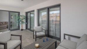 A modern living room with a sofa, armchairs, a coffee table, and a potted plant. - Apartman Blue in Poreč (Poreč)