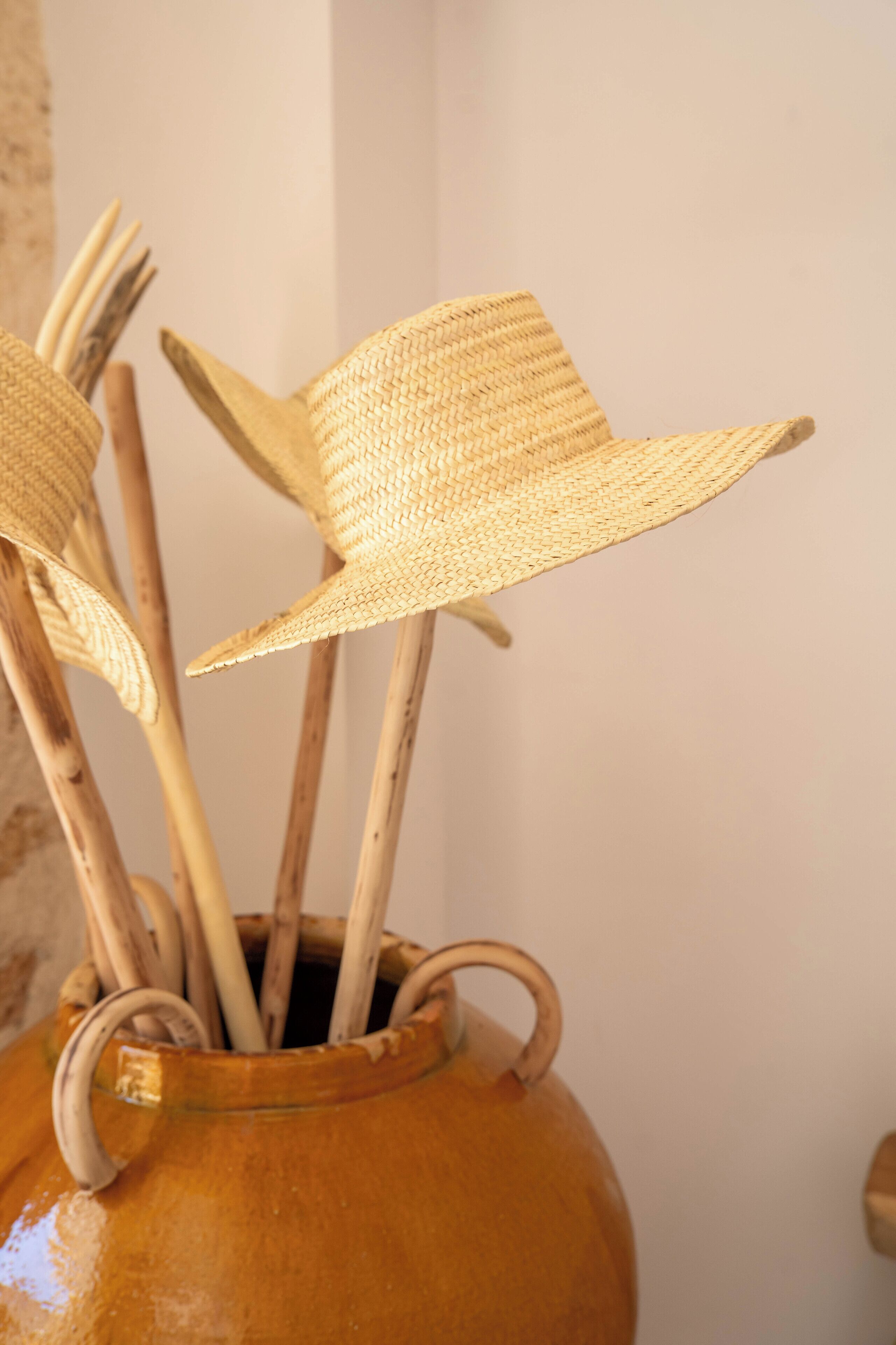 A vase with several straw hats.
