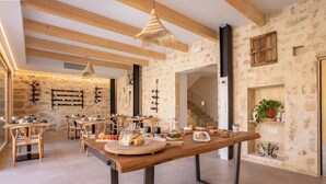 Un interior rústico con paredes de piedra vista, vigas de madera y una larga mesa de madera dispuesta con comida y bebidas.