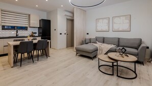A modern living space with a dining area, a grey sofa, and a round coffee table. - Valley View 2 Bedroom Villa with Private Pool (Zakinthos)