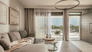 A modern living room with a sofa, a small round table, and a view of a balcony with outdoor furniture. - Valley View 2 Bedroom Villa with Private Pool (Zakinthos)