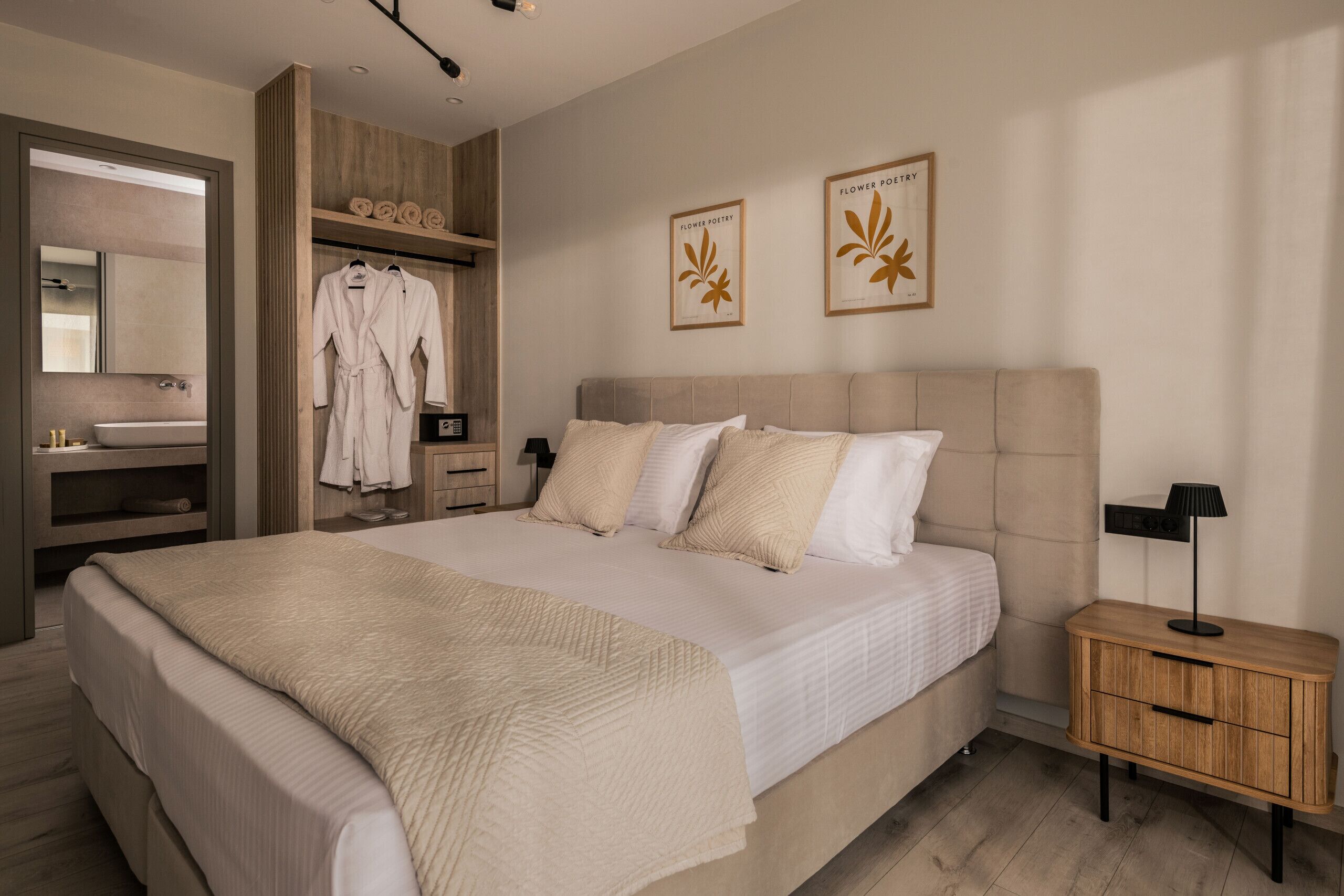 A modern bedroom with a large bed, a wooden nightstand, a bedside table, a wardrobe, and two framed artworks on the wall.