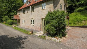 A stone house with a red-tiled roof, a covered porch, and a well-maintained garden. - Keepers Cottage (Devizes)