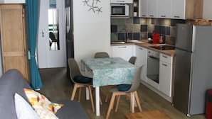 A compact kitchen with a dining area, a microwave, a refrigerator, and a wooden cabinet.