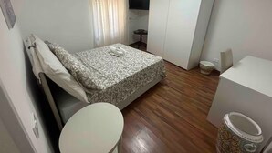 A small, well-lit bedroom with a bed, a bedside table, a toilet, and a wardrobe. - B&B Anna e Gaetano (Meta)