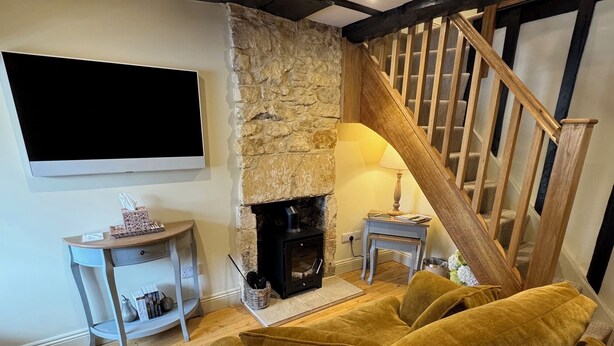 Un salon doté d’une cheminée en pierre, d’un escalier en bois et d’un téléviseur à écran plat fixé au mur.