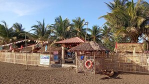Zona de playa con una estructura de techo de paja, un área cercada con un flotador salvavidas y un letrero que dice 'Leonor Beach Resort'.