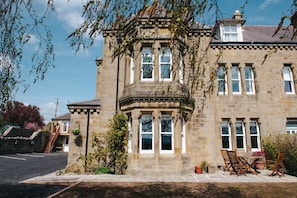 A stone building with a bay window, a staircase, and outdoor seating. - Eastfield Lodge - Perfect Group accommodation (Leyburn)