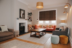Una sala de estar con chimenea, un sofá, una mesa de centro y una estantería.