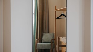 Une pièce comprenant une armoire en bois, une chaise et un porte-vêtements.