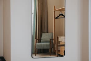 Una habitación con un armario de madera, una silla y una percha.