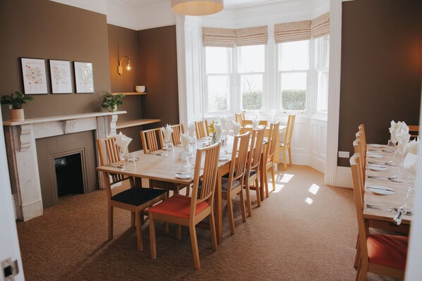 A dining area with a fireplace, wooden chairs, and a table set for six.