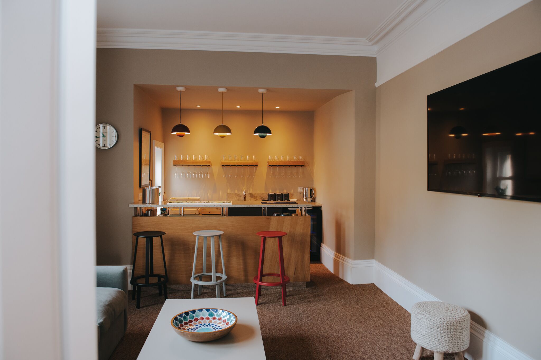 Une cuisine moderne dotée d’un éclairage suspendu, d’un coin bar et d’un espace repas avec des tabourets.