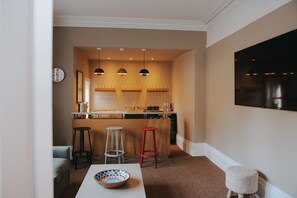 Uma cozinha moderna com iluminação pendente, um espaço bar e uma área de refeições com banquetas.