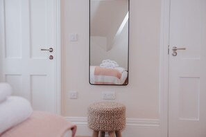 Une salle de bain avec une porte blanche, un miroir et un porte-serviettes avec des serviettes.