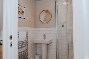 A bathroom with a white sink, a glass shower enclosure, and a towel rack.