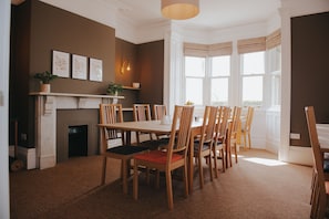 Un comedor con chimenea, sillas de madera y un ventanal con cortinas.