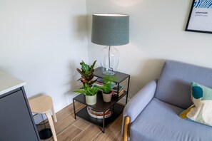 A modern living room with a grey sofa, a small side table with a lamp, and a potted plant. - Eastfield Lodge - Perfect Group accommodation (Leyburn)