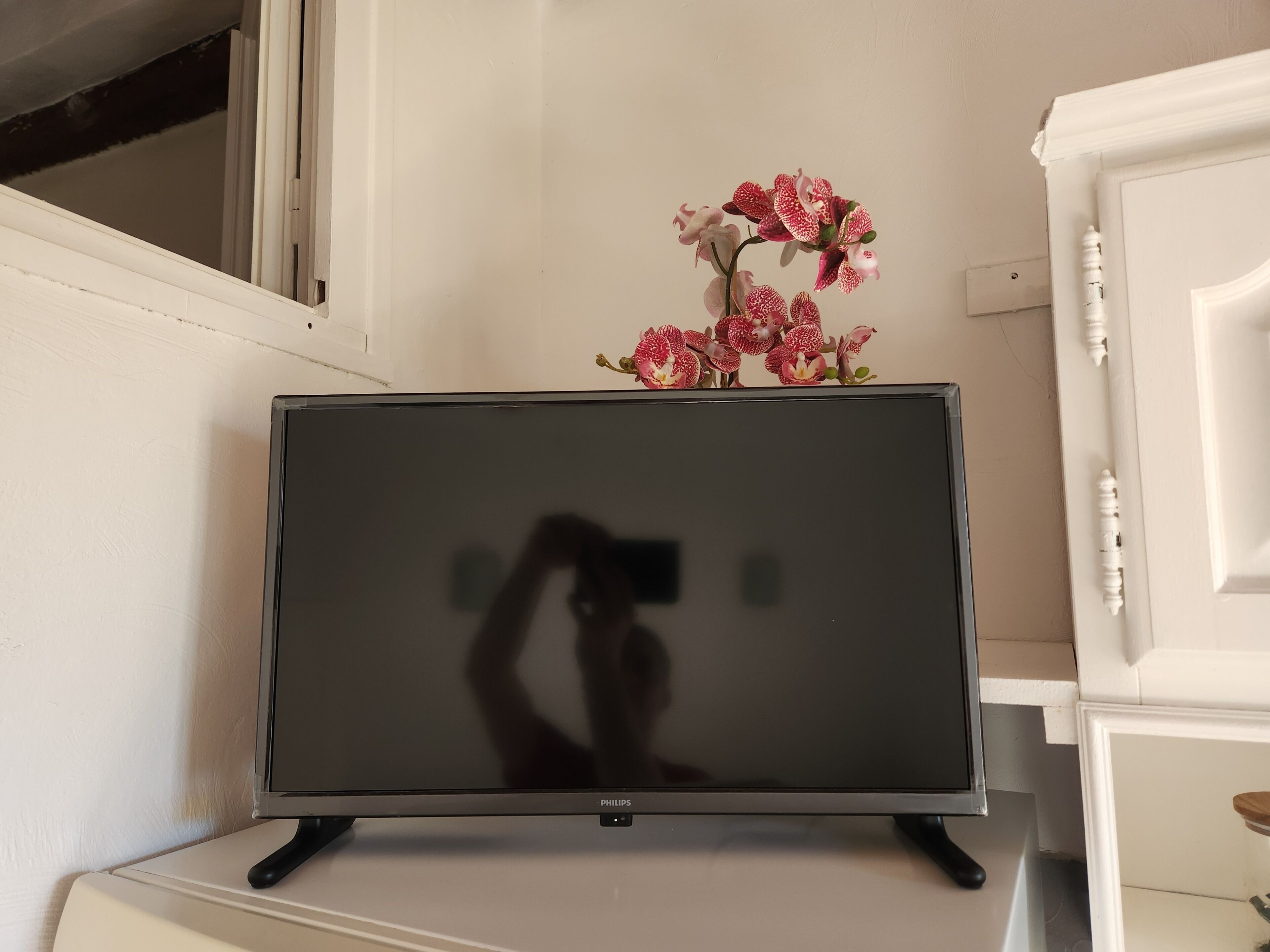 A television on a stand with a floral arrangement on top.