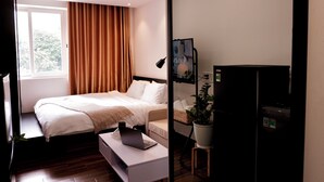 Une chambre d’hôtel moderne équipée d’un lit, d’un bureau avec un ordinateur portable, d’une télévision, d’une plante et d’une fenêtre avec des rideaux.