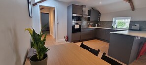 Una cocina moderna con gabinetes grises, un horno de acero inoxidable y una ventana con vistas a zonas verdes.