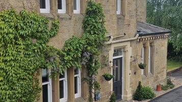Un edificio de piedra con varias ventanas y una estructura pequeña adosada.
