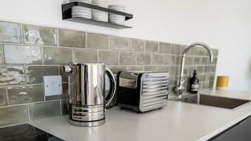 A kitchen with a coffee maker, toaster, and a shelf with containers.