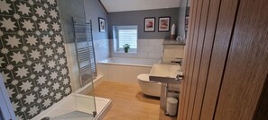 A bathroom with a shower, toilet, and sink. There is a window with blinds and a plant on the windowsill. - The Drey Apartment - self-catered Dales luxury (Leyburn)