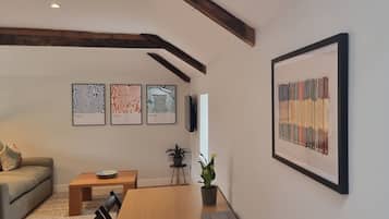 A living room with a wooden table, a sofa, and three framed abstract artworks on the wall.