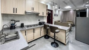 Una cocina moderna con una isla central, taburetes de bar, horno empotrado y microondas.