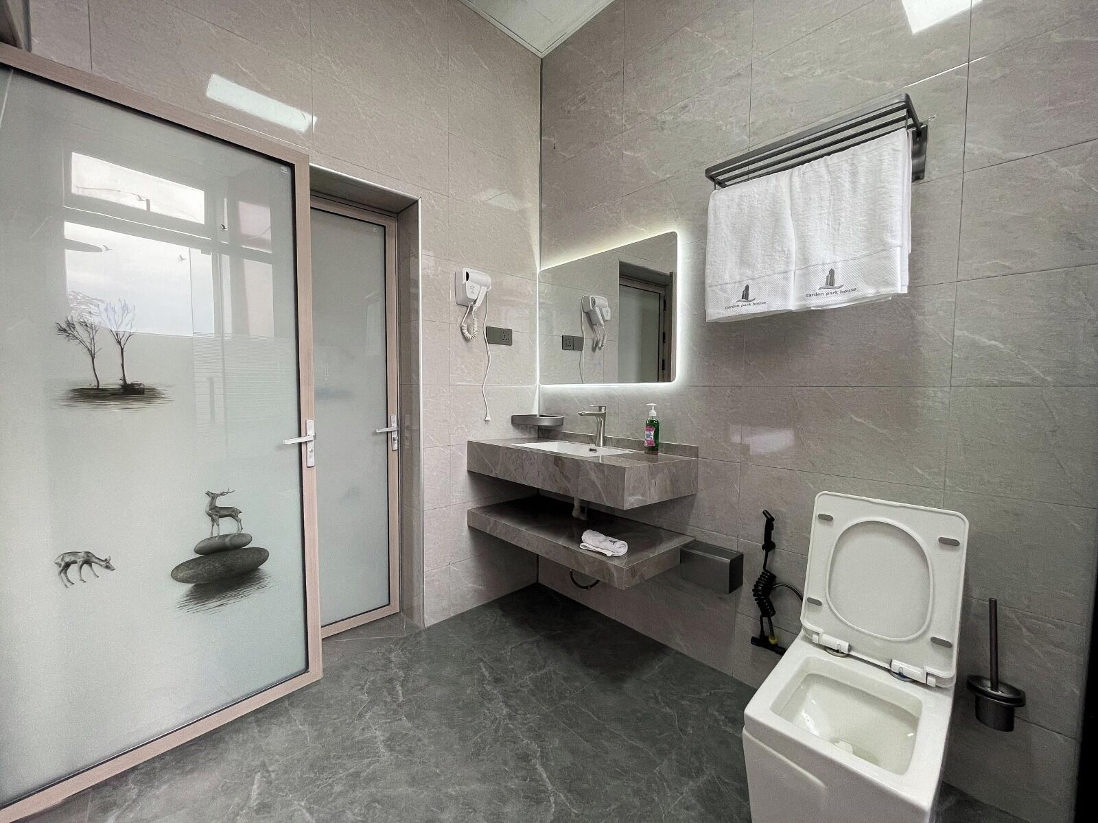 Une salle de bain moderne avec une douche à parois de verre, un lavabo en marbre et des toilettes.