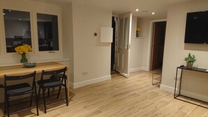 A modern kitchen with a wooden countertop, two black chairs, and a vase of yellow flowers. - Modern Self-catering Apartment - The Holt (Leyburn)