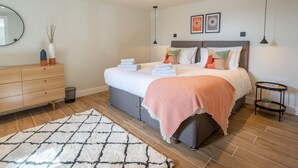 A modern bedroom with a bed, dresser, and bedside tables. - Modern Self-catering Apartment - The Holt (Leyburn)