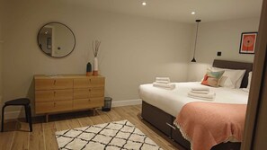 Een slaapkamer met een bed, een kaptafel, een spiegel en een vloerkleed.