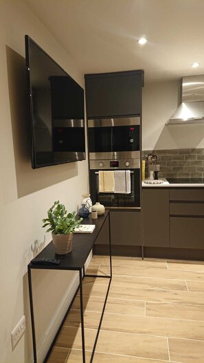 Een moderne keuken met een inbouwoven, een magnetron en een flatscreen tv aan de muur.