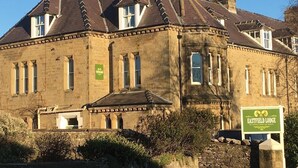 A historic building with a stone facade, multiple windows, and a green sign indicating it is Eastfield Lodge.