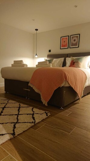 A bedroom with a bed, a bedside table, a lamp, and a rug. - Modern Self-catering Apartment - The Holt (Leyburn)