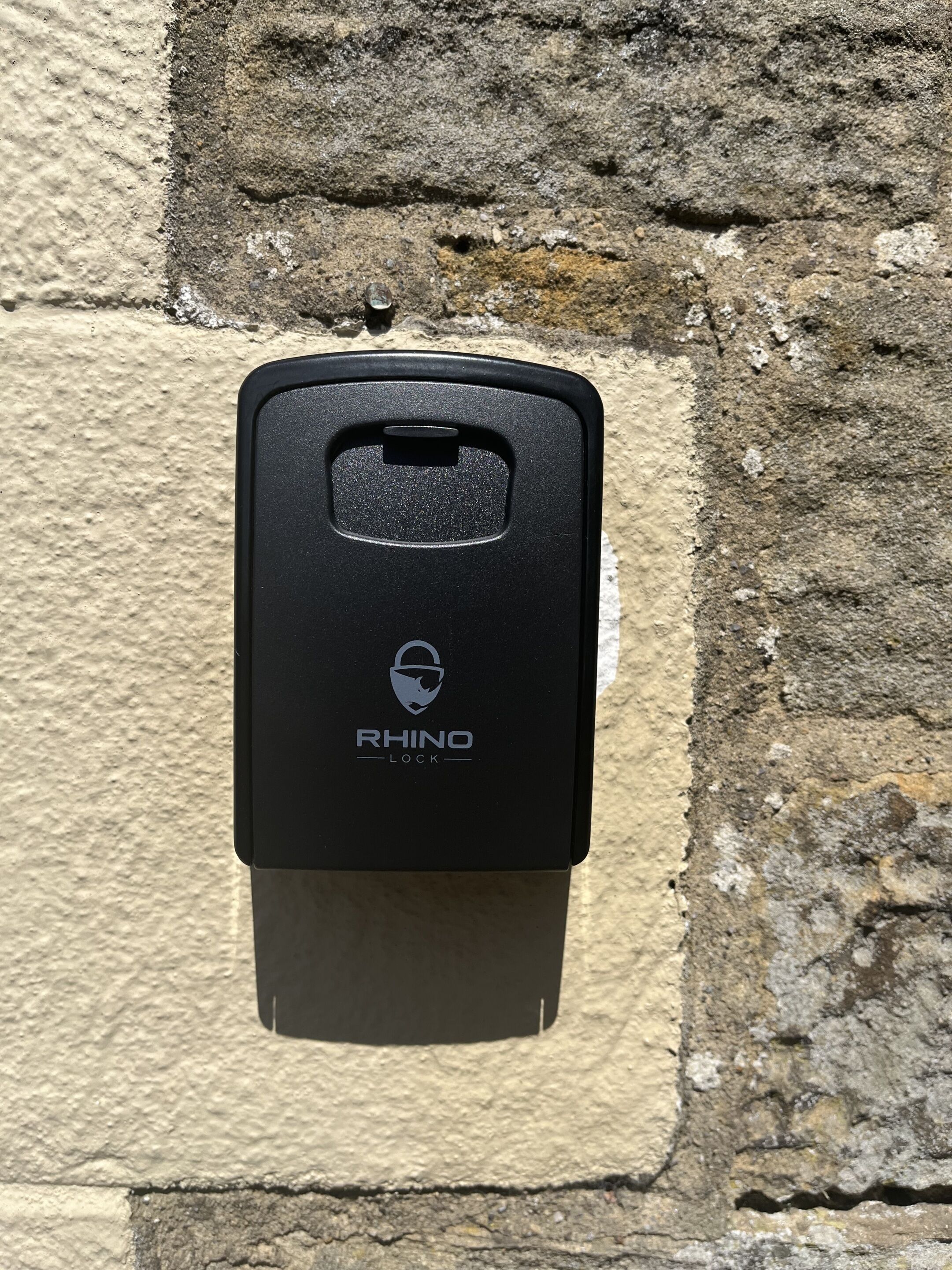 Ein schwarzer RHINO LOCK Wertschließfach an einer Steinwand befestigt.