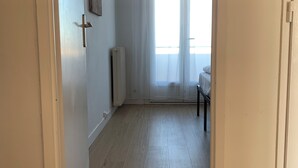 A room with a wooden floor, a radiator, a bed, and a chair. - Panoramic view of Clape (Narbonne)