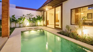 A modern house with a swimming pool, large windows, and a well-maintained garden.