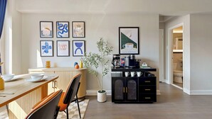 A modern kitchen with a dining area, featuring a coffee station, framed artwork on the wall, and a potted plant. - Arlington 1BR • Metro Access • Free Parking (Arlington)