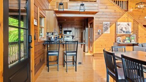 L’intérieur d’un chalet en bois comprend une cuisine, un coin repas et un escalier menant à une mezzanine.
