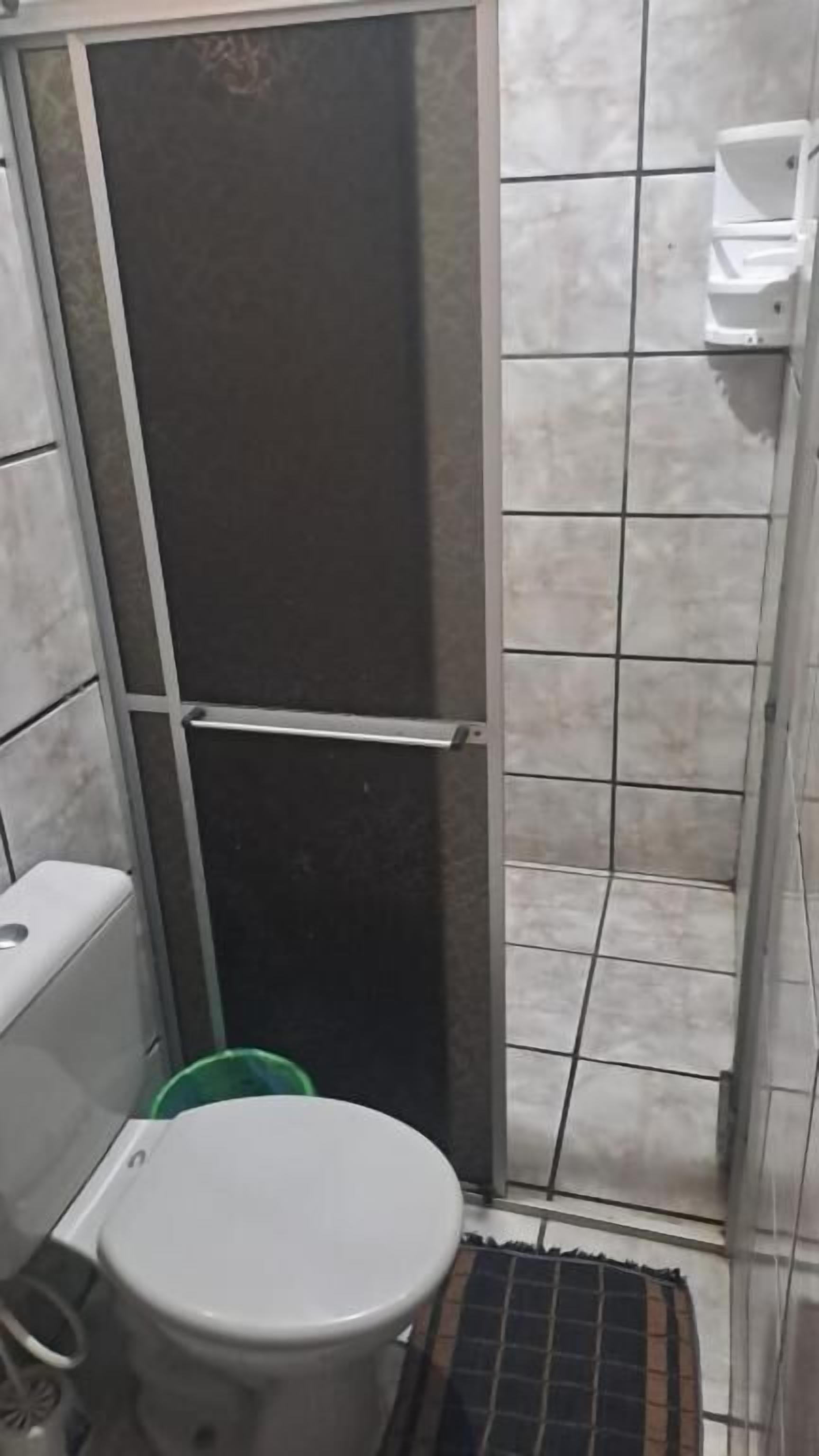 Un bagno piccolo con un water, uno spazio doccia e una parete piastrellata.