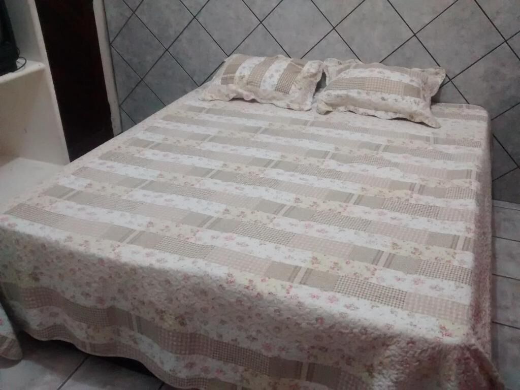 Una cama con una colcha de estampado floral y dos almohadas.