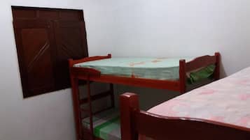 A small room with a bunk bed, a wooden door, and a window.