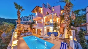 A modern hotel with a pool, multiple balconies, and outdoor seating.