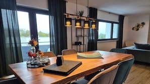 Een moderne eetruimte met een houten tafel, stoelen en een bloevas.