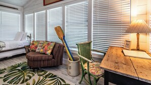 Una habitación acogedora con una cama, un sillón mullido, una mesa de madera y una lámpara.